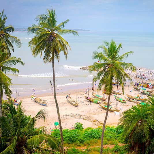 A beach with people and colorful fishing boats on it.