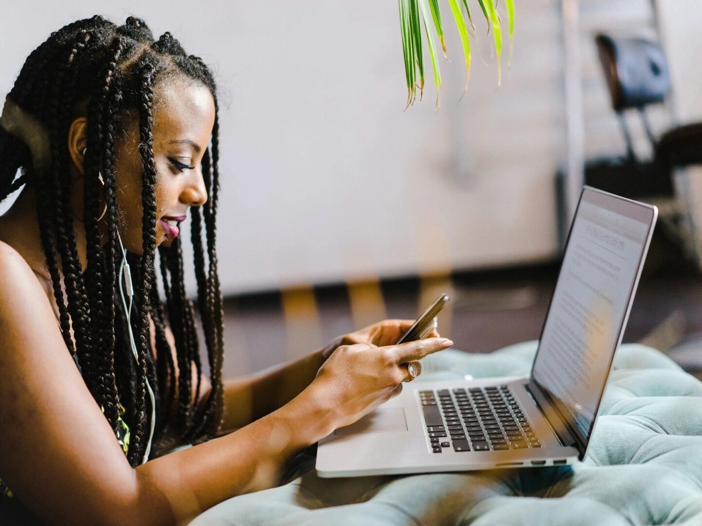 Woman looking at cell phone and computer.